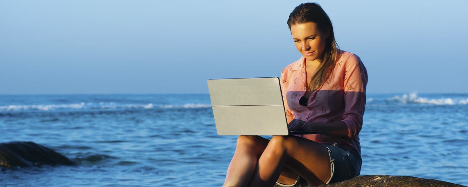 Girl with a laptop on the beach